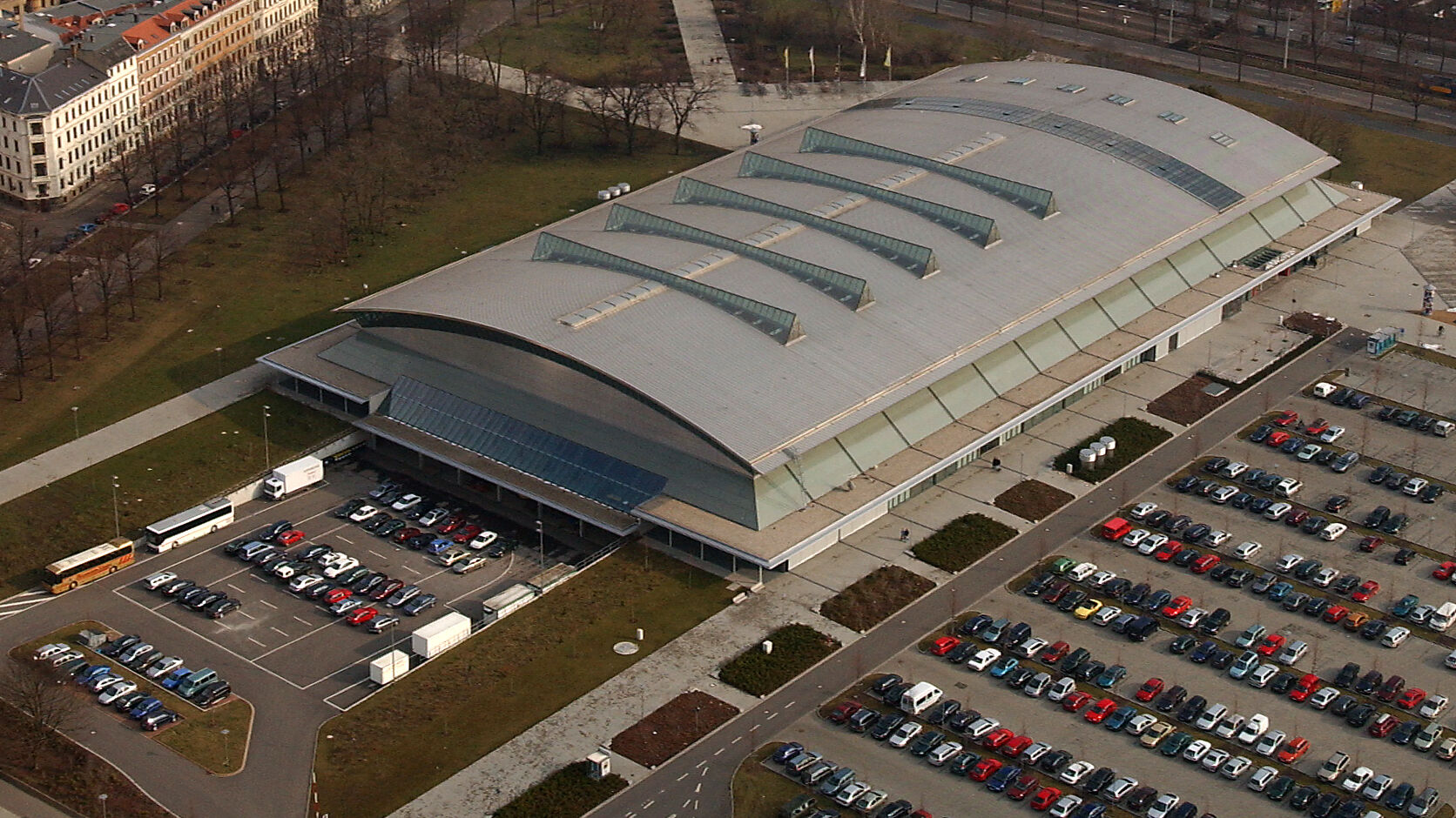 Luftaufnahme der QUARTERBACK Immobilien ARENA mit ihren Parkplätzen und der Stadt Leipzig im Hintergrund.